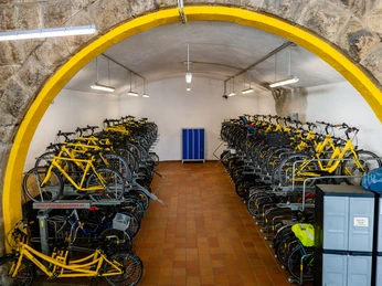 Radstation Köln Fahrradstation in Köln mit gelben Fahrrädern in einem gewölbten Raum unter Steindecke abgebildet.Bicycle station in Cologne with yellow bicycles pictured in a vaulted room under a stone ceiling.