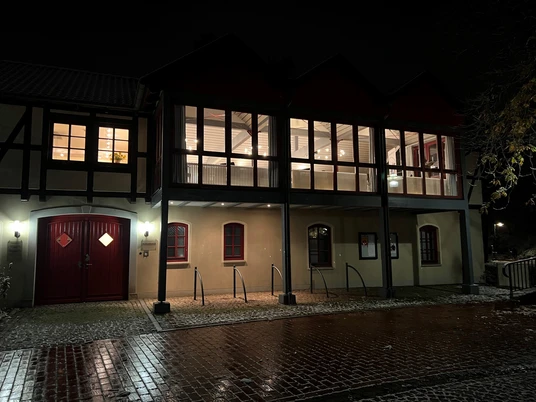 Historisches Fachwerkgebäude bei Nacht, beleuchtet mit warmem Licht und reflektierten Pflastersteinen.