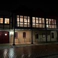 Bürgerhaus Uchte Historisches Fachwerkgebäude bei Nacht, beleuchtet mit warmem Licht und reflektierten Pflastersteinen.