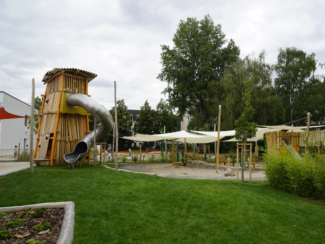 AbenteuerDorf Kids Campus - Familienurlaub in Leipzig Ein große Röhrenrutsche schlängelt sich aus dem hölzernen Turm des Abenteuerspielplatz.A large tube slide winds its way out of the wooden tower of the adventure playground.Z dřevěné věže dobrodružného hřiště se vine velká trubková skluzavka.Duża zjeżdżalnia rurowa wije się z drewnianej wieży przygodowego placu zabaw.Een grote buisglijbaan baant zich een weg uit de houten toren van de avonturenspeeltuin.Un grande scivolo a tubo si snoda dalla torre di legno del parco giochi.