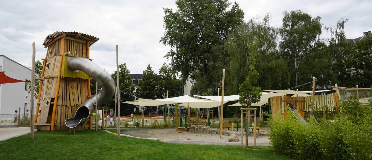 Adventure Village Kids Campus - rodzinne wakacje w Lipsku Duża zjeżdżalnia rurowa wije się z drewnianej wieży przygodowego placu zabaw.