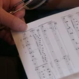 Eine Hand hält ein Notenblatt in der Hand.
