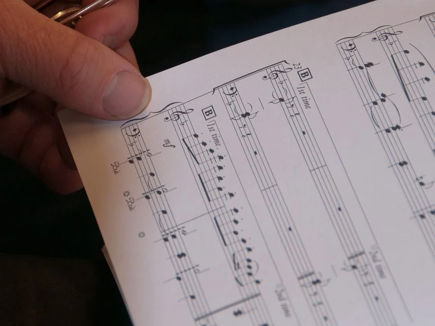 Eine Hand hält ein Notenblatt in der Hand.
