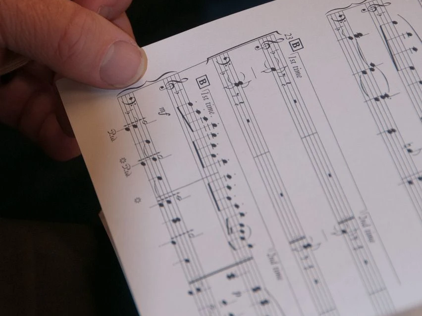 Chorkonzert Eine Hand hält ein Notenblatt in der Hand.