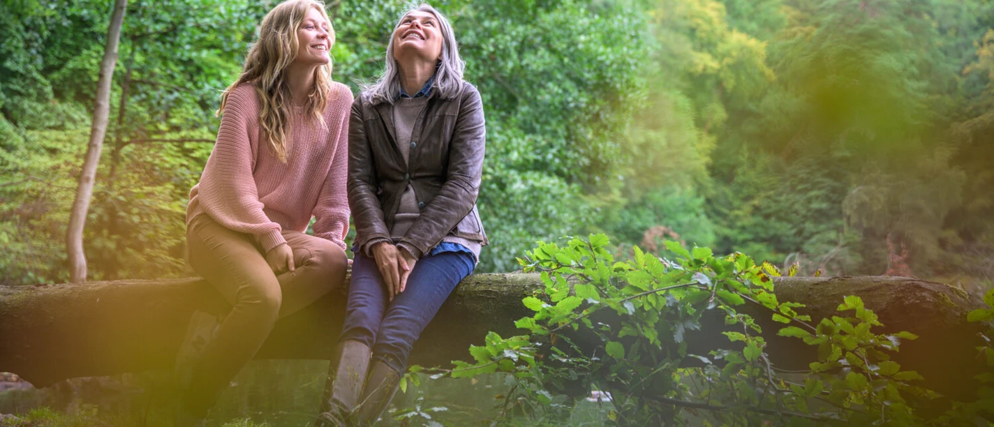 Waldspaziergang_AlexKMedia (2).jpg Zwei Frauen sitzen im Wald auf einem Baumstamm