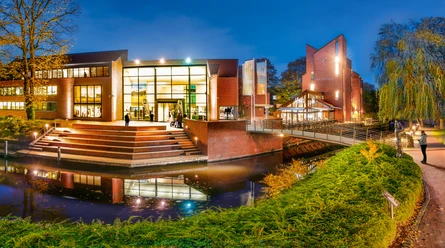 Kunsthalle-Emden_Foto-Bühler -141.jpg Exterior view of the Kunsthalle in the evening. The entrance is on a wide staircase, with trees and canals in the background."