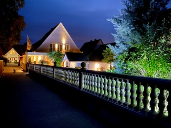 Wilsmann Apartements Hövelhof Wilsmann Apartments Hövelhof bei Nacht, beleuchtet mit umgebenden Pflanzen und einem dekorativen Zaun.