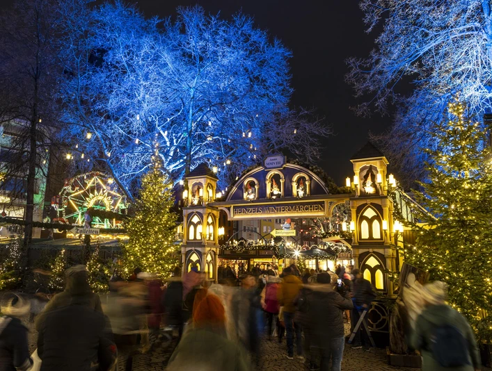 Heinzels Wintermärchen Der Weihnachtsmarkt auf dem Alter Markt in Köln strahlt im Lichterglanz mit Festdekoration und festlichem Torbogen, eingerahmt von blauen Bäumen.The Christmas market on the Alter Markt in Cologne shines in a blaze of lights with festive decorations and a festive archway, framed by blue trees.De kerstmarkt op de Alter Markt in Keulen schittert in een vuurzee van lichtjes met feestelijke decoraties en een feestelijke boog, omlijst door blauwe bomen.