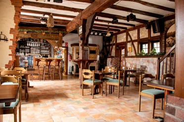 Kaffee Hexenbrink Innenansicht Rustikales Restaurant mit Holzbalken, gemütlicher Atmosphäre, Holztischen und hoher Decke im Landhausstil.