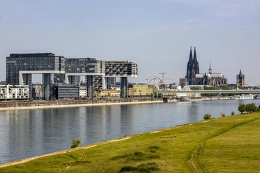 Rheinauhafen Die modernen Kranhäuser am Rheinufer mit dem Kölner Dom im Hintergrund bei klarem Himmel.