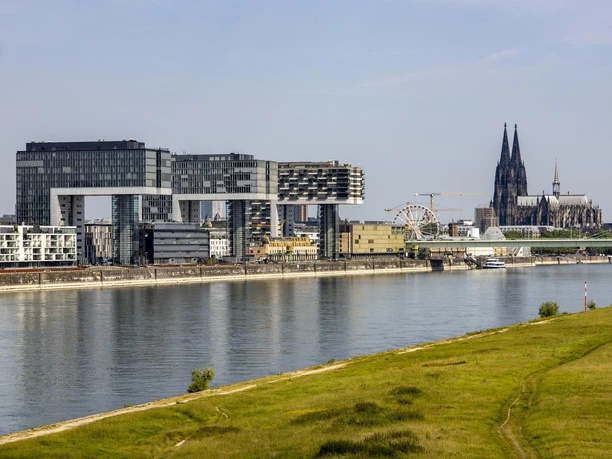 Rheinauhafen The modern crane houses on the banks of the Rhine with Cologne Cathedral in the background under a clear sky.