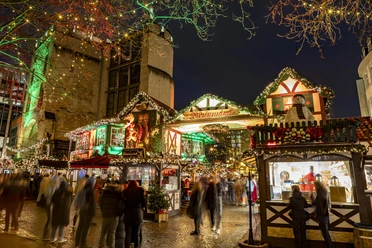 Village of St. Nicholas at Rudolfplatz Lively Christmas market in Cologne at night, decorated huts, colorful lights illuminate the square.