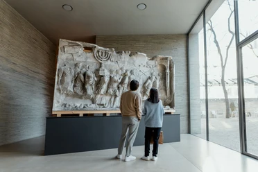 Kolumba In the Kolumba Museum in Cologne, two people look at a large, antique relief on a modern exhibition wall.