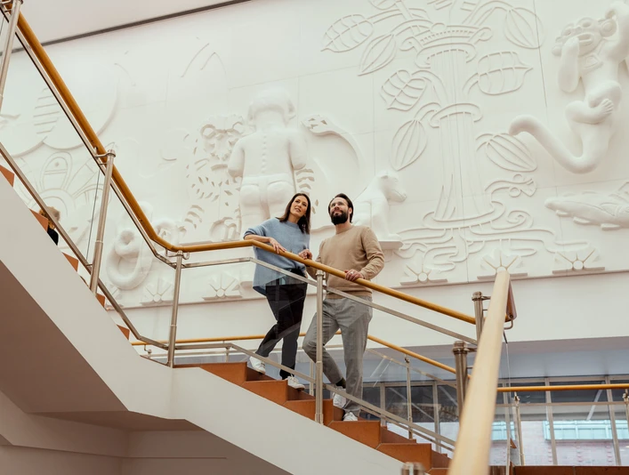 Museum Ludwig Das Bild zeigt zwei Personen, die eine Treppe im Museum Ludwig in Köln hinaufgehen, vor einer kunstvoll gestalten Wandgestaltung.The picture shows two people walking up a staircase in the Museum Ludwig in Cologne, in front of an artistically designed mural.