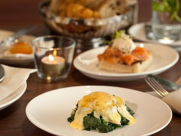 Mill'Feuille breakfast with eggs on spinach, yoghurt, pastries and salmon on a table