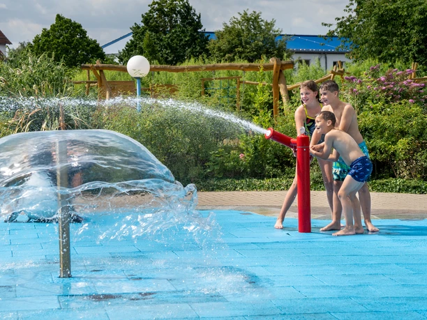 Spielende Kinder im RIFF Bad Lausick - Freizeitbad in der Leipzig Region Drei Kinder spielen am Outdoor-Wasserspielplatz des Freizeitbades RIFF in Bad Lausick mit Wasserkanonen, Familienausflug, Freizeit, Badespaß