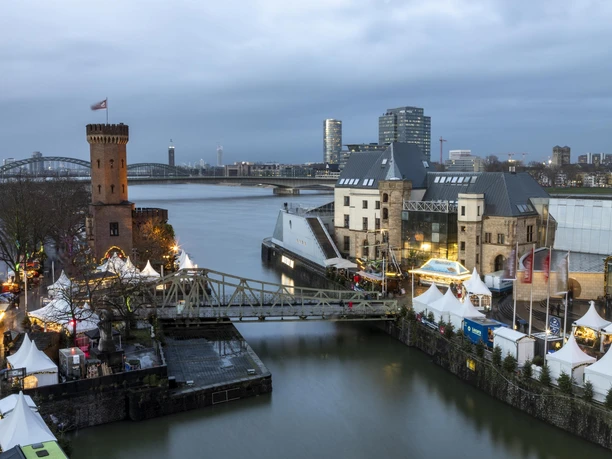 Kölner Hafen-Weihnachtsmarkt Festlich beleuchteter Weihnachtsmarkt am Schokoladenmuseum Köln mit Zelten, Brücke und Rheinblick.