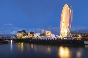 Kölner Hafen-Weihnachtsmarkt Abendstimmung am Rhein: Weihnachtsmarkt mit Lichtern, markantem Schokoladenmuseum und Riesenrad.