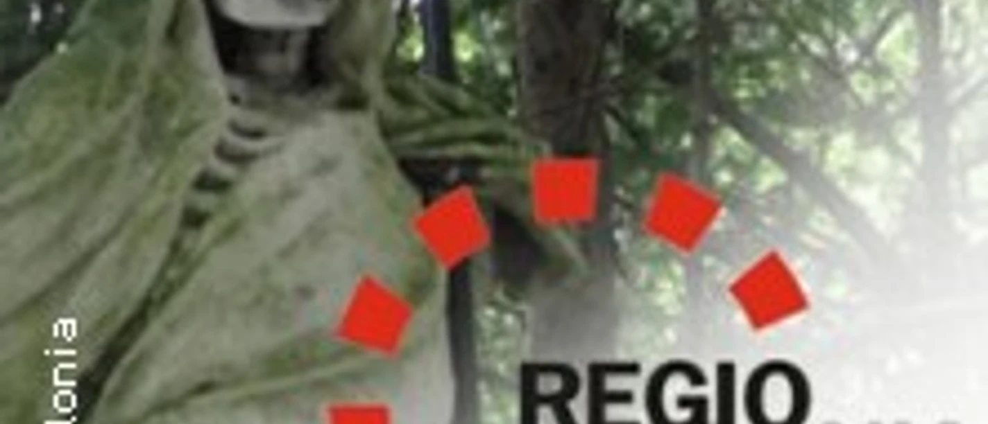 Eine steinerne Figur eines Skeletts, von einem Umhang umgeben, steht in einem von Bäumen beschatteten Bereich.