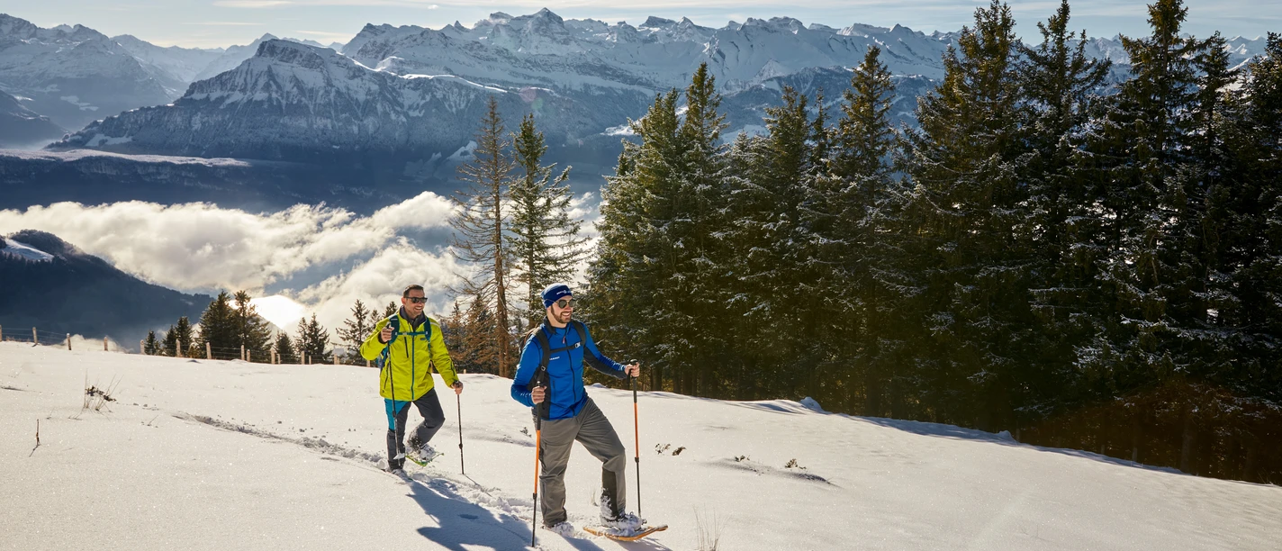 Schneeschuhtouren Personen stapfen mit Schneeschuhen durch die tiefverschneite Rigi-Landschaft