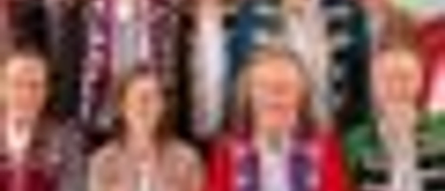 Neun Personen in traditioneller rheinischer Karnevalstracht vor buntem Hintergrund.