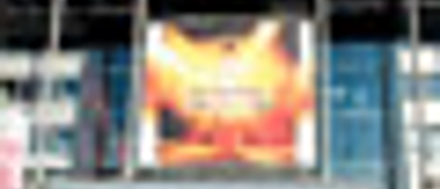 Außenansicht eines Gebäudeeingangs mit einem großen, leuchtenden Werbebanner.