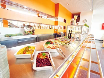 Moderne Kantine mit Selbstbedienung. Lange Theke mit verschiedenen Salaten und Antipasti in Schalen.