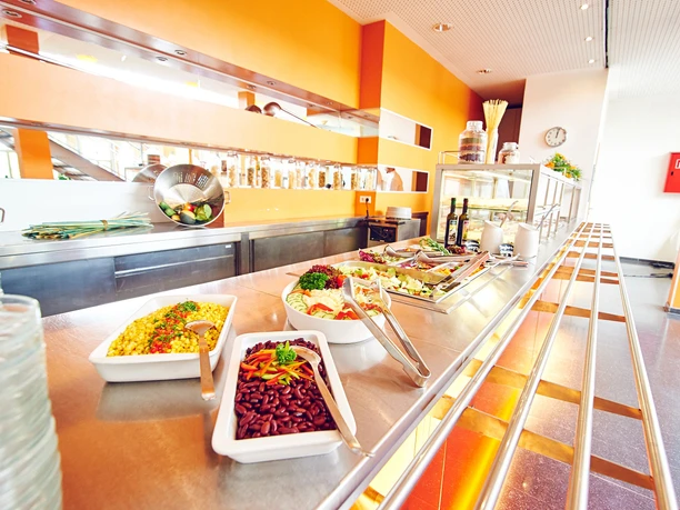 Jugendgästehaus_Bielefeld_2018_Speisesaal.jpg Moderne Kantine mit Selbstbedienung. Lange Theke mit verschiedenen Salaten und Antipasti in Schalen.