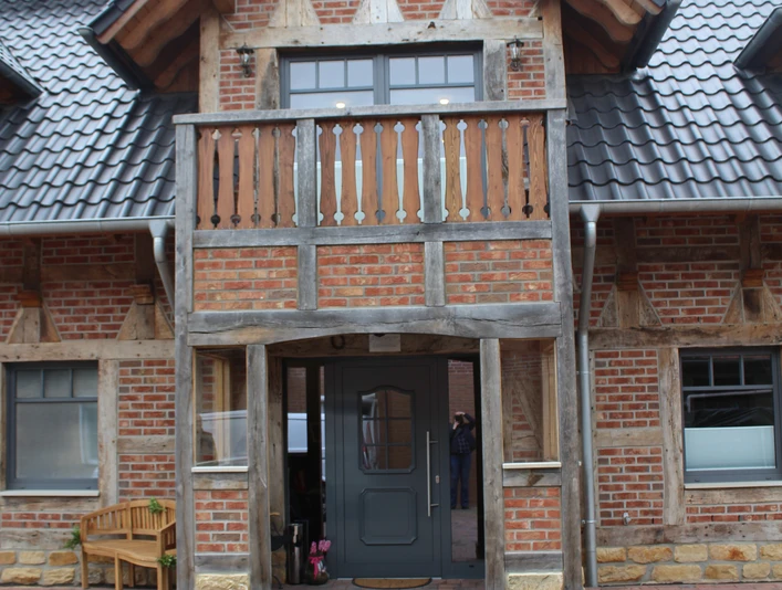 Gästehaus Rehburger Landhaus Rotes Backsteingebäude mit Fachwerkdetails und einem Balkon, umgeben von gepflasterten Flächen.