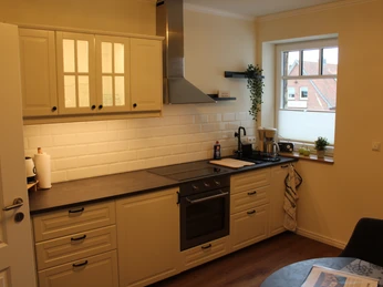 Gästehaus Rehburger Landhaus Klassische Küche mit heller Einrichtung, modernem Herd, weißen Fliesen und Fenster mit Blick ins Freie.