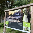 Liewerfrauenweg Holzrahmen mit Info-Tafel über den Liewerfrauenweg in einer grünen Waldumgebung.