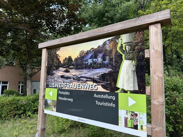 Liewerfrauenweg Holzrahmen mit Info-Tafel über den Liewerfrauenweg in einer grünen Waldumgebung.