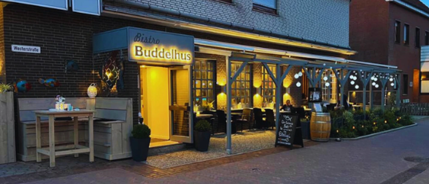 The exterior view of the Buddelhus, a cozy bistro in Borkum, at twilight.