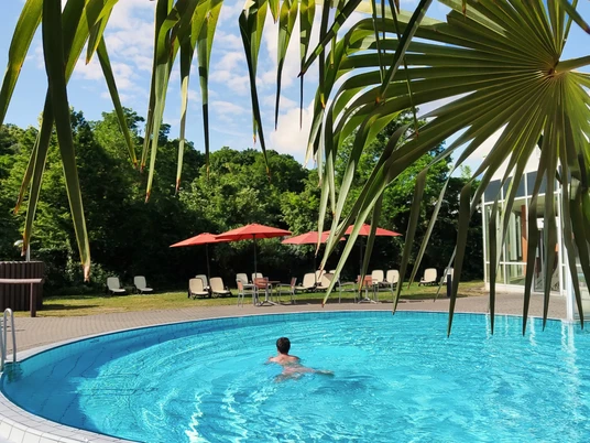 Saunawelt im HEIDE SPA Bad Düben - Wellness in Leipzig und Region Ein Mann schwimmt im Pool der Badelandschaft des Saunabereichs im Heide Spa Bad Düben bei sonnigem Wetter, Ausflug, Wellness, Freizeit