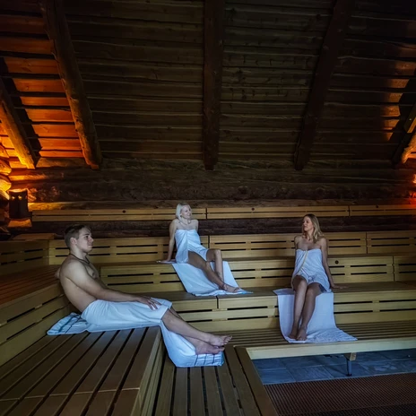 Tři osoby přikryté ručníkem, sedí v sauně ve srubu a relaxují v lázních Heide Bad Düben, wellness, relaxace, výlet