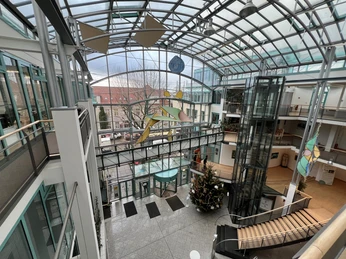 Offenes Atrium im Rathaus Achim mit Glasdach, gläserne Aufzüge und weihnachtlich dekorierter Baum.