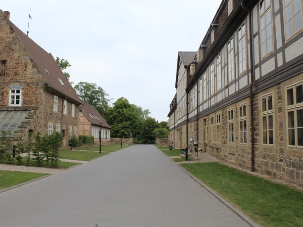 Kloster Loccum Breiter, gepflasterter Weg umgeben von historischen Gebäuden des Klosters Loccum, umgeben von Grün.
