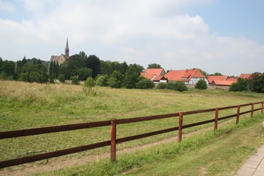 Kloster Loccum Kloster Loccum mit rotem Ziegeldach und Kirchturm inmitten grüner Wiesen und bewaldeter Hügel.