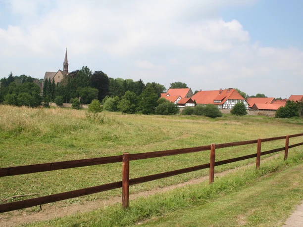 Kloster Loccum Kloster Loccum mit rotem Ziegeldach und Kirchturm inmitten grüner Wiesen und bewaldeter Hügel.