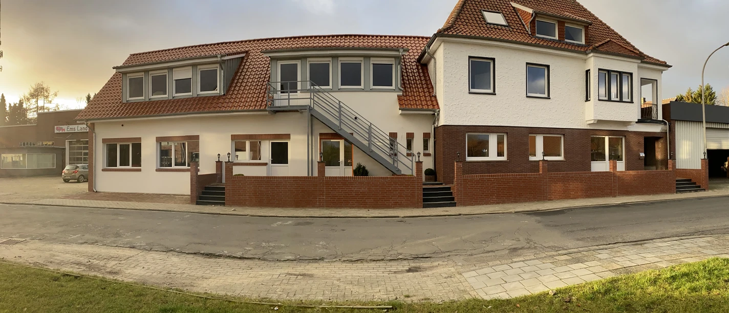 Tempel-inn, Molkereisr.2, Werlte.JPEG Zweigeschossiges Gebäude mit rotem Ziegeldach, weißen Fassaden und Außentreppe bei Abendlicht