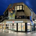 Tourist Information Paderborn mit leuchtendem Eingang in moderner Architektur bei Dämmerung.