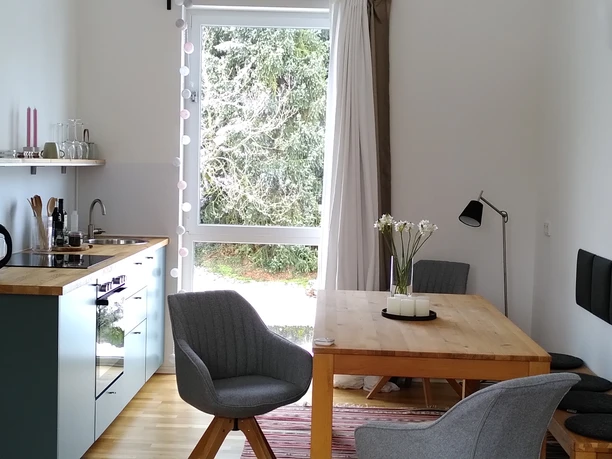 Ferienwohnung Zeitraum Modern eingerichtete Küche und Essbereich mit skandinavischem Design, Holzdetails und großen Fenstern.