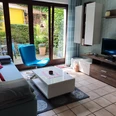 Wohnzimmer Helles Wohnzimmer mit Sofa, Sessel, Fernseher, Couchtisch und großer Fensterfront zum Garten.