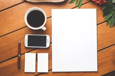 Seminar Kaffeetasse, Handy, Stift, leeres Papier und Visitenkarten auf Holztisch.