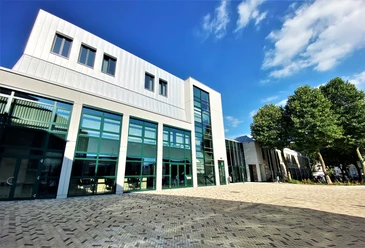 Forum Velbert Moderne Architektur des Forum Velbert mit großen Glasfassaden und angrenzenden Bäumen unter blauem Himmel.