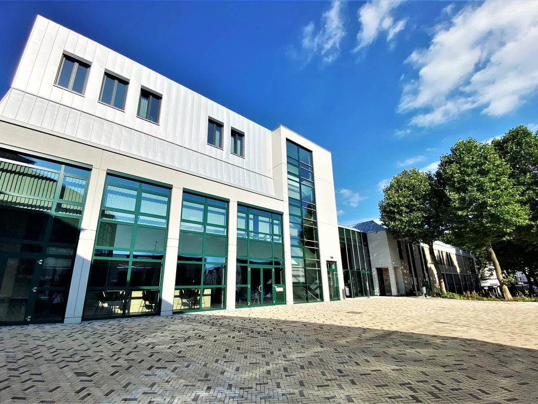 Forum Velbert Moderne Architektur des Forum Velbert mit großen Glasfassaden und angrenzenden Bäumen unter blauem Himmel.