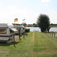 Campingplatz Achim-Bollen Ruhiger Campingplatz in Wassernähe mit Wohnwagen und Fahnen im Sommer, umgeben von grüner Natur.