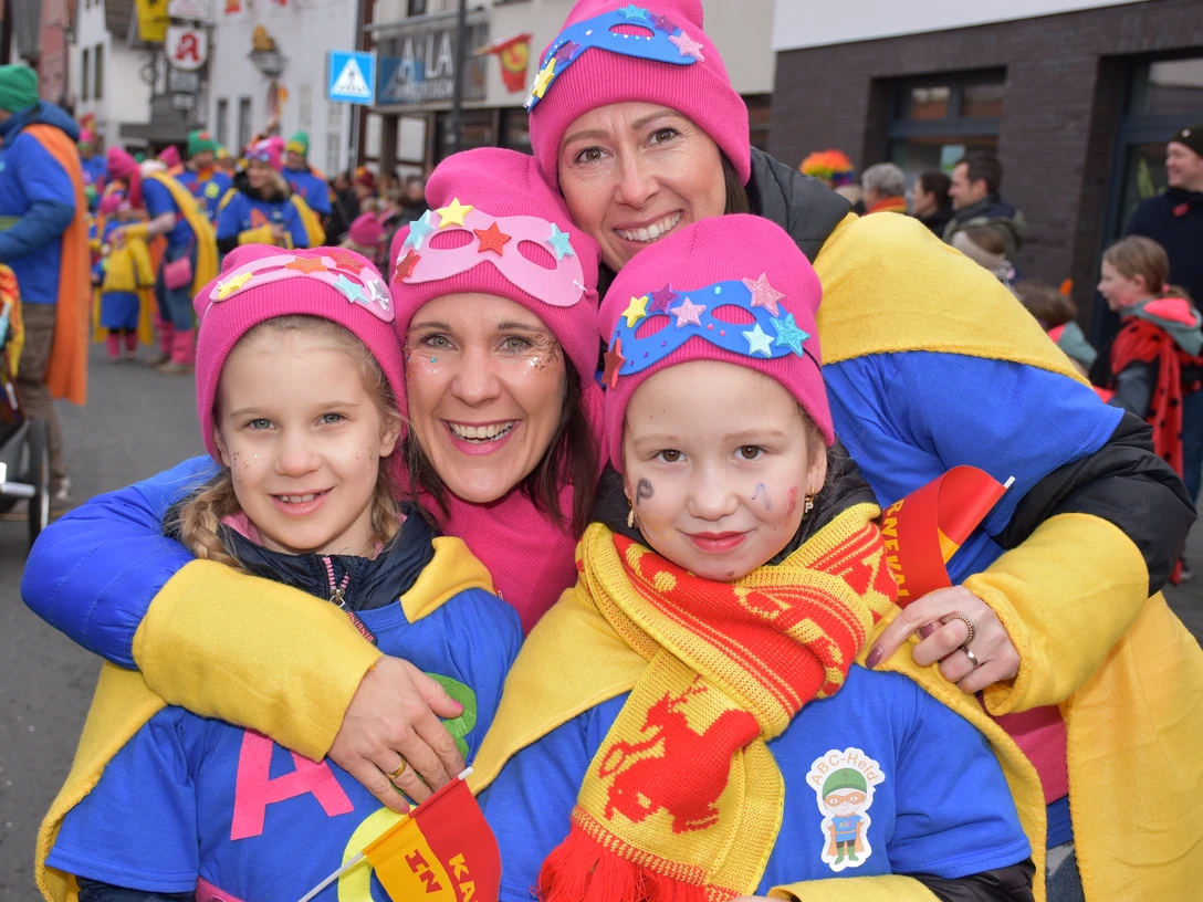 KVE_8758.JPG Menschen in bunten Karnevalskostümen lächeln fröhlich in die Kamera, umgeben von feiernden Personen.