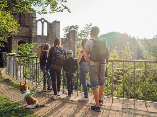 Burg Oybin Eine Familie mit Hund steht auf einem Weg vor der Ruine von Burg Oybin, bei Sonnenuntergang.