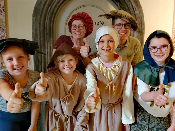 Museum Eine Gruppe in mittelalterlichen Kostümen vor einem historischen Museumseingang.